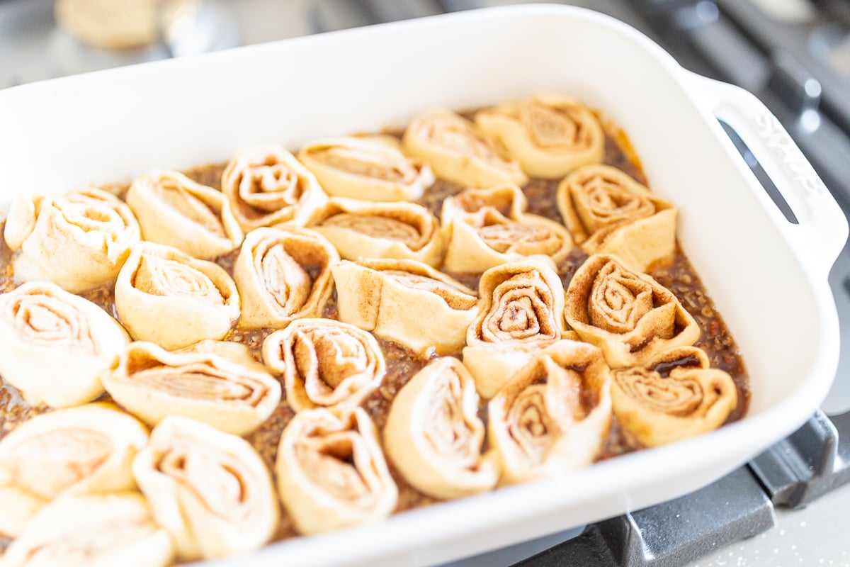 A white baking dish filled with pecan rolls.