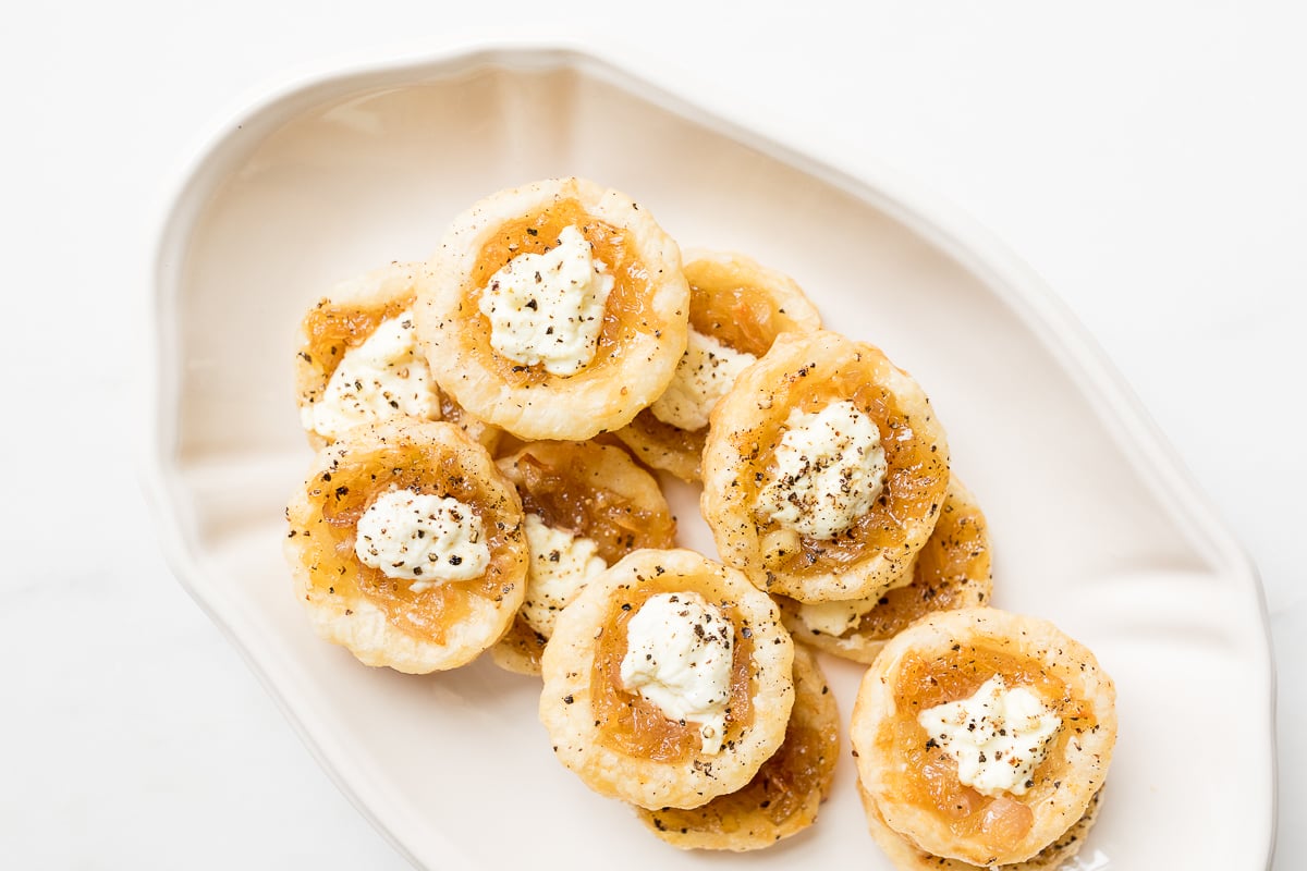 Caramelized shallot tarts on a white platter.