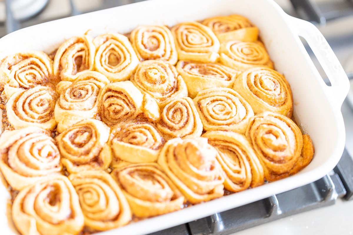 Pecan rolls in a baking dish on top of a stove.