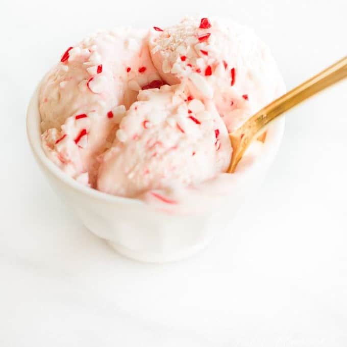 A white bowl full of homemade peppermint ice cream, gold spoon sticking out.