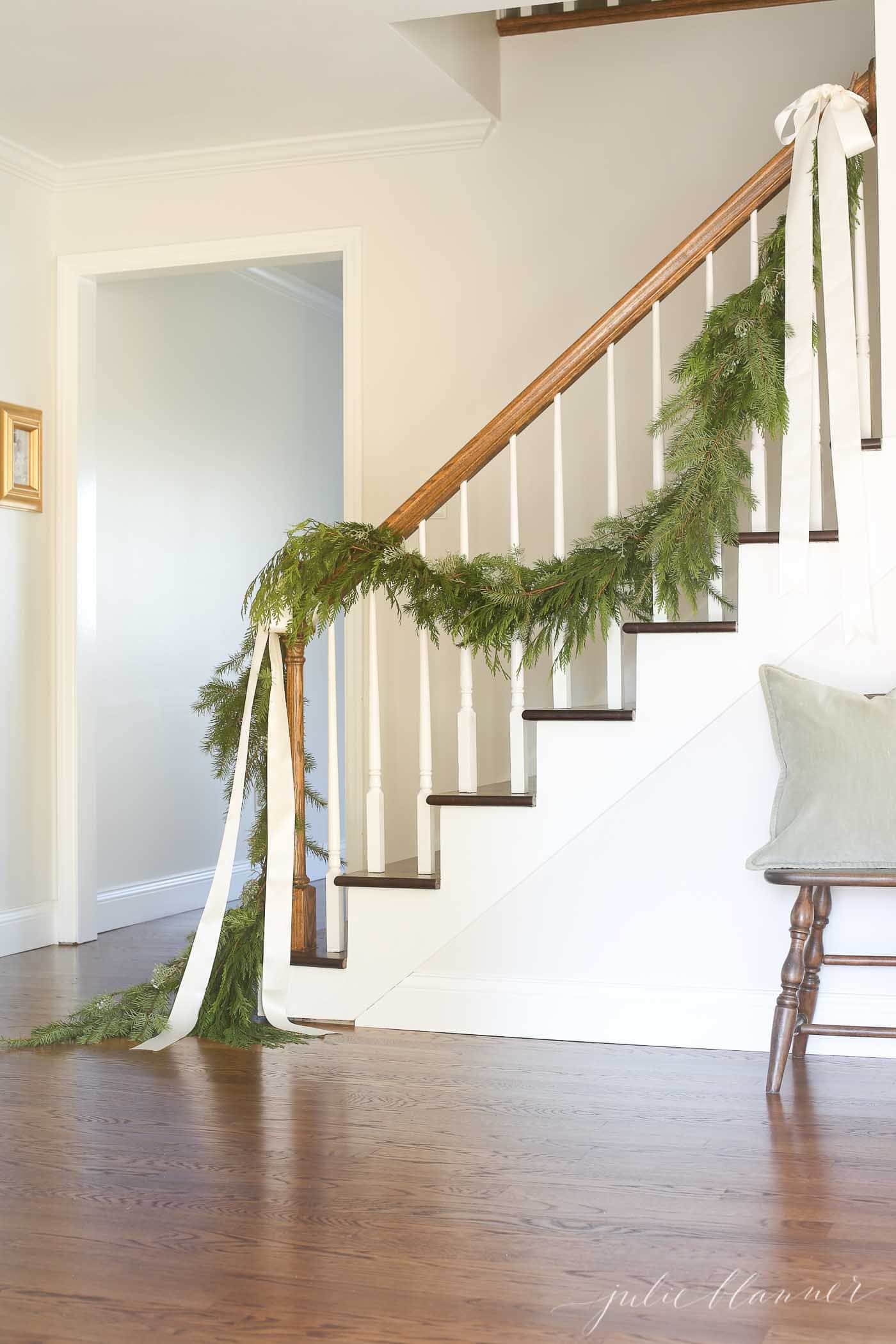 traditional stair garland tied on with ribbons in a white entryway