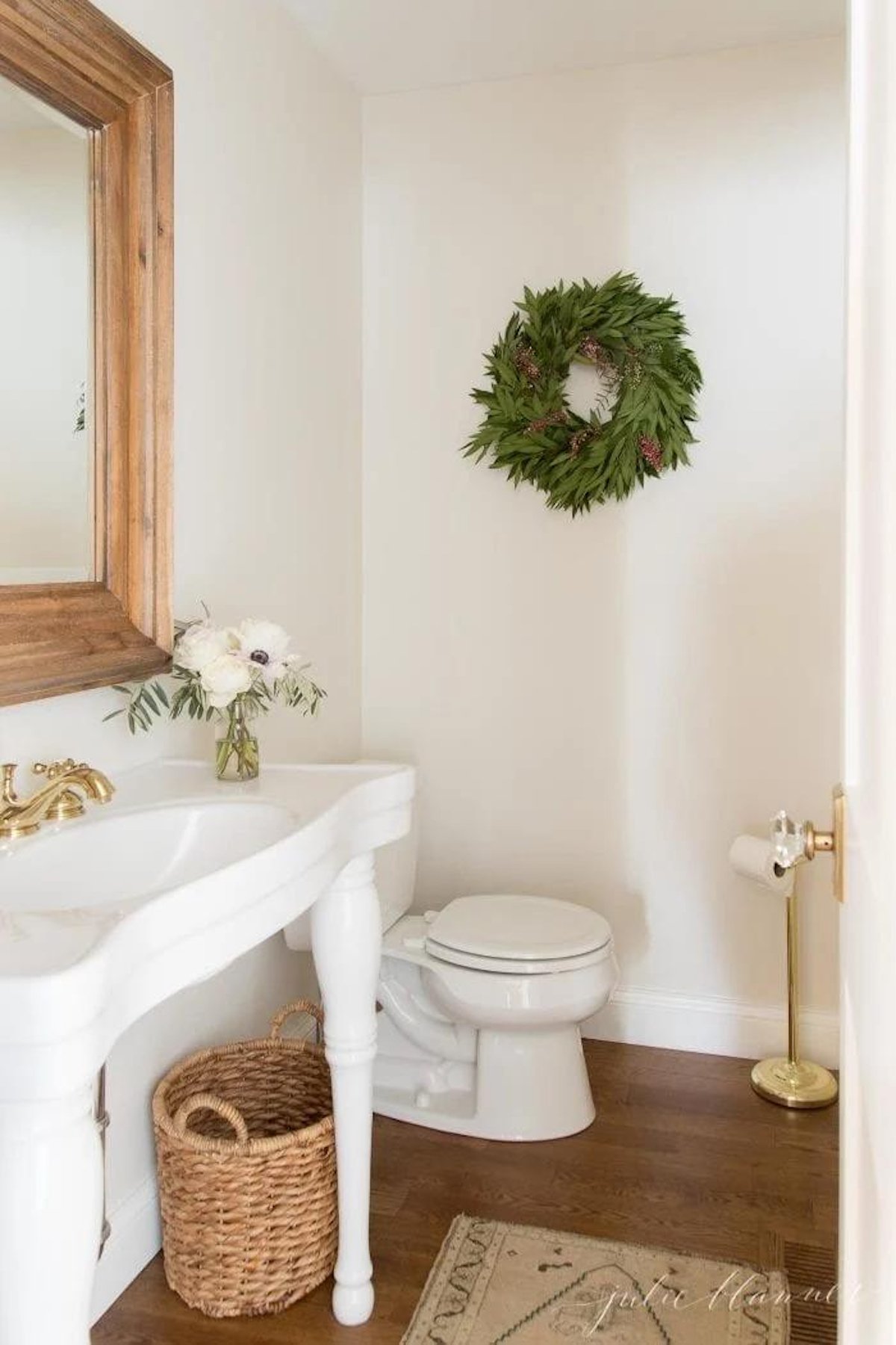 A white bathroom adorned with a festive wreath hanging on the wall, bringing a touch of Christmas cheer to your house.