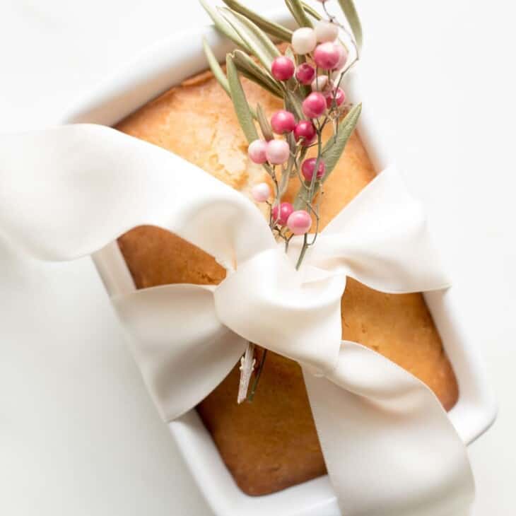 almond bread in loaf pan wrapped in ribbon with berries to gift