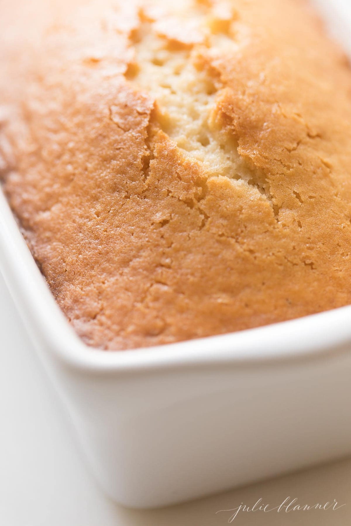 A loaf of quick almond bread in a ceramic loaf pan