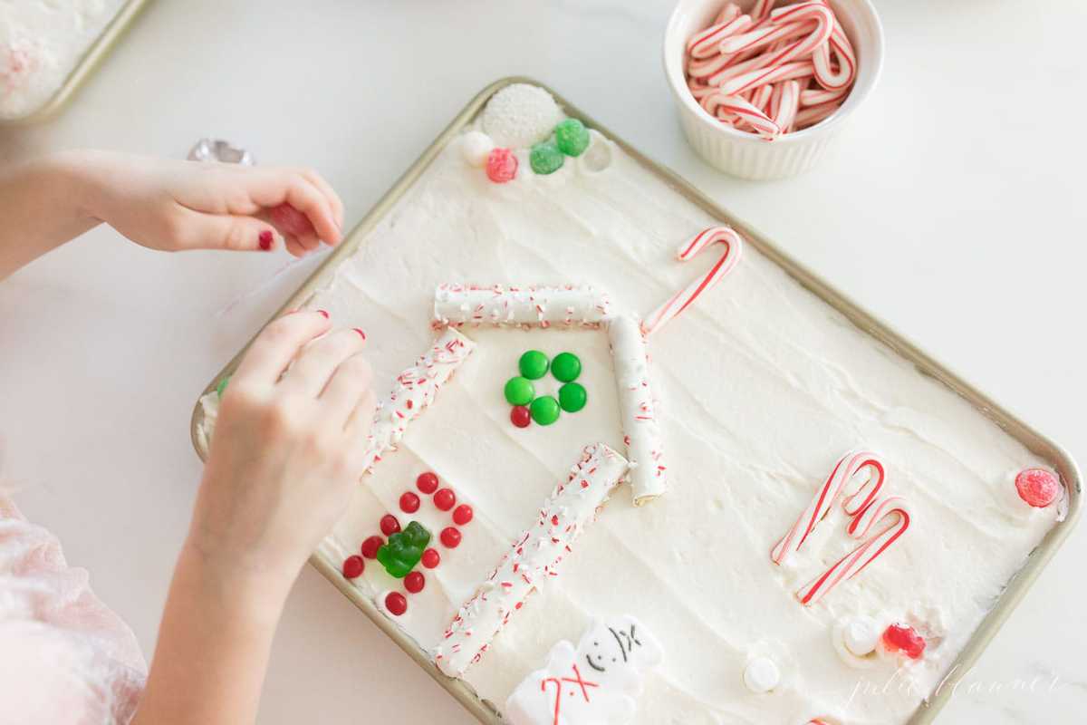 girl decorating christmas cookie sugar cookie cake gingerbread house