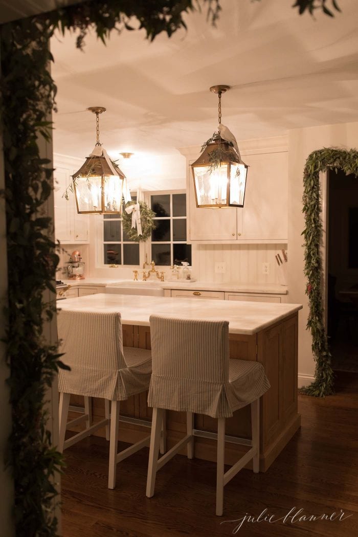 A kitchen with brass lantern pendant lights decorated for christmas with garlands and wreaths