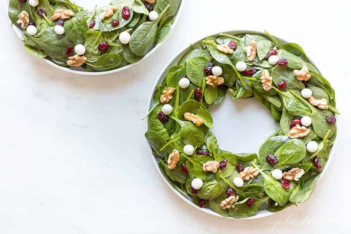 artfully displayed salads on white platters, shaped to look like a christmas wreath.