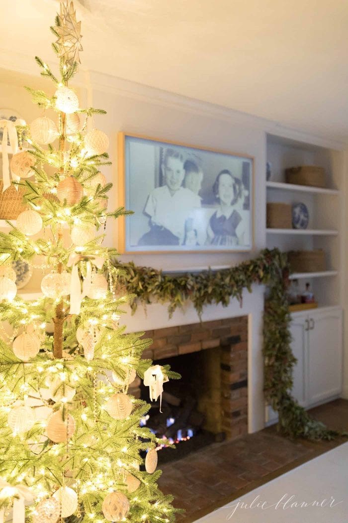 A living room with a christmas tree and garland on a fire place. 