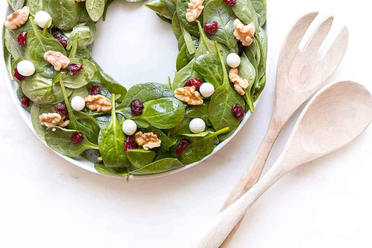 Christmas wreath salad in a white bowl with salad servers