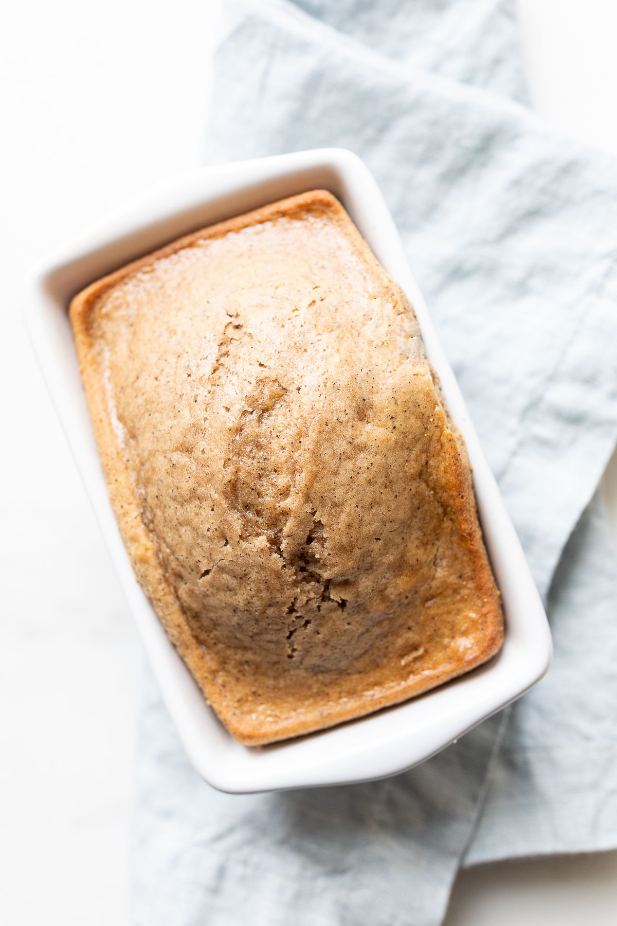 A quick latte bread in a small white loaf pan, on a blue kitchen towel. 