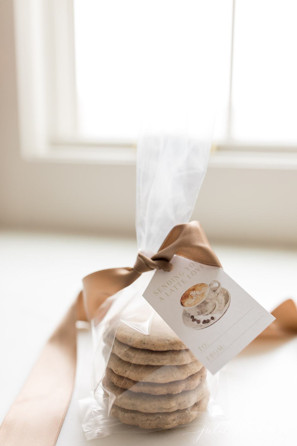 stacked espresso cookies wrapped in cellophane and tied with a brown satin bow and gift tag.