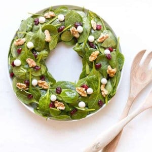 salad in shape of wreath with toppings to look like berries next to wood salad tongs