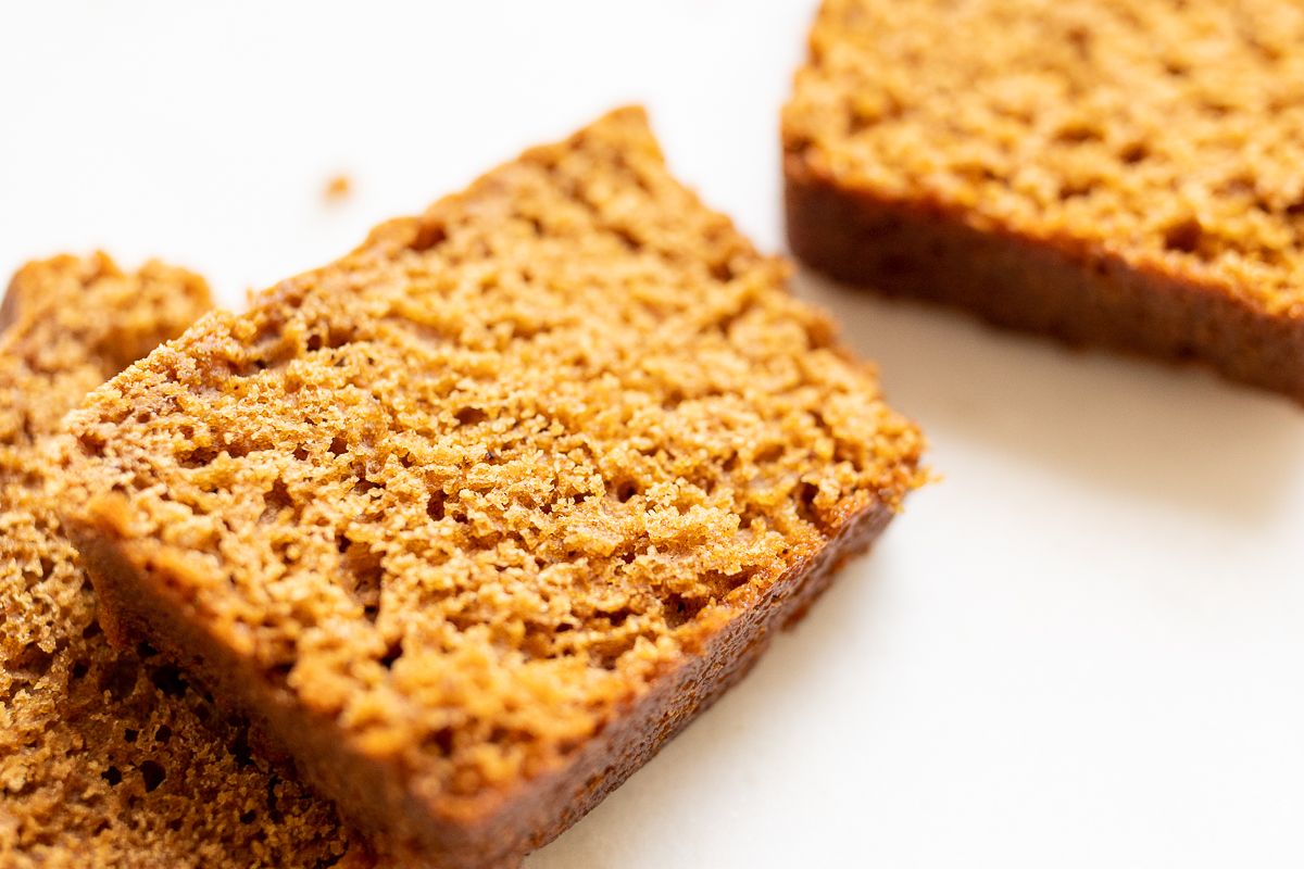 Slices of a gingerbread loaf recipe on a white marble countertop.