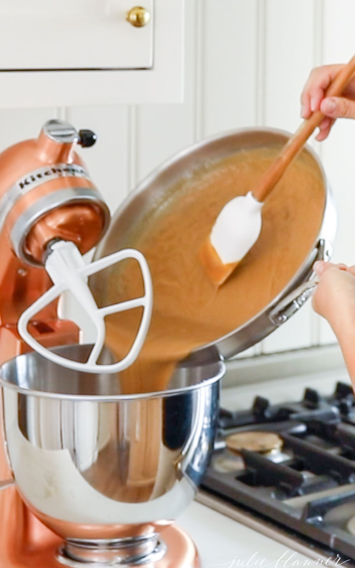 A copper stand mixer with ingredients for peanut butter fudge being added in by a pair of hands.