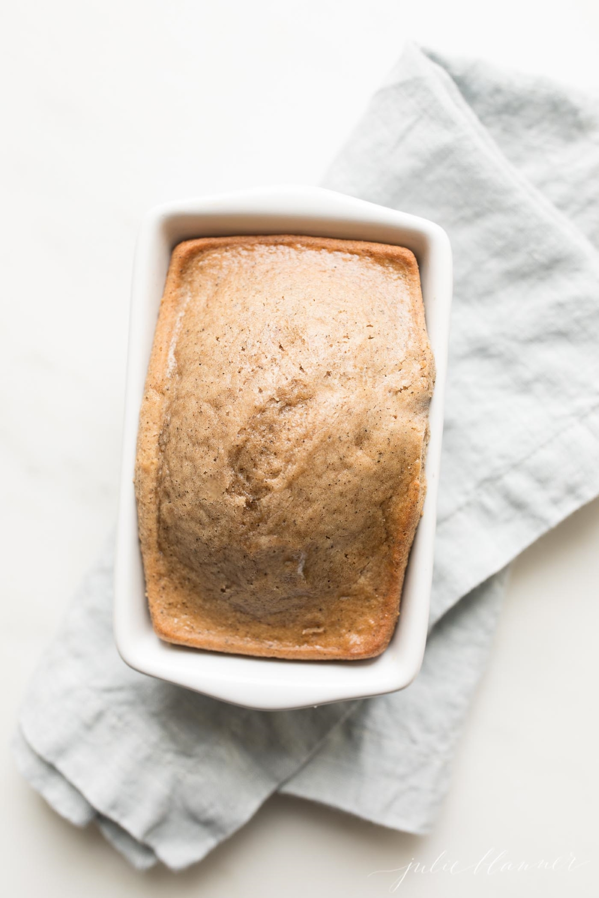 An espresso bread in a small white loaf pan, on a blue kitchen towel.
