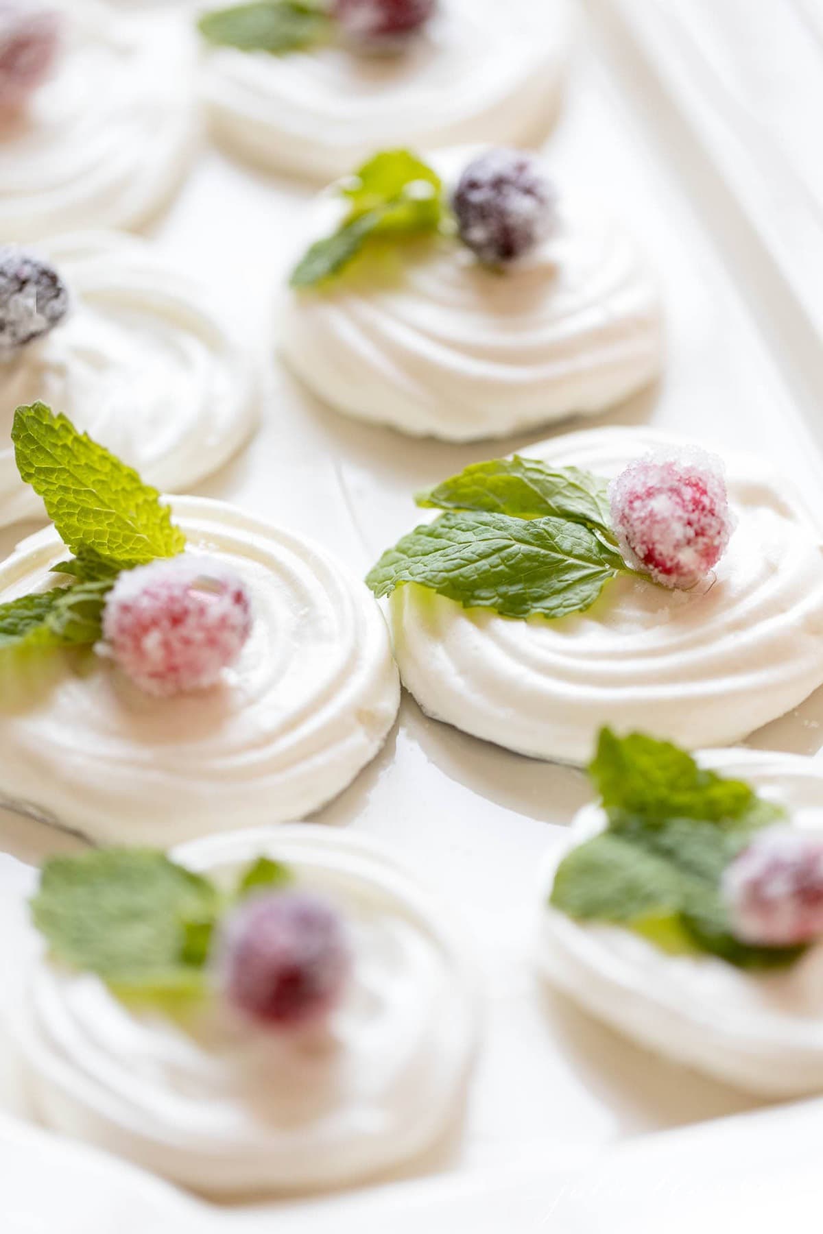 meringue cookies decorated with mint leaves and sugared cranberries