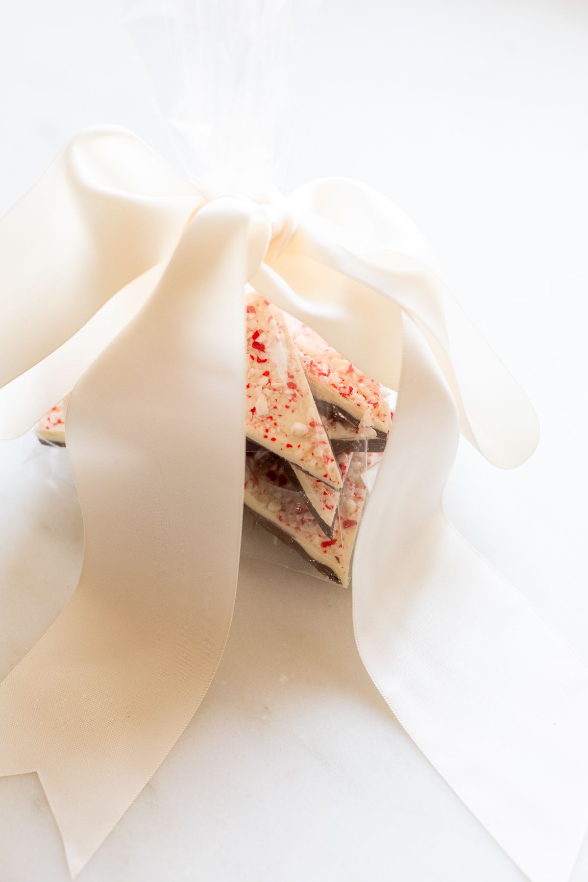 Peppermint bark wrapped in a cellophane bag and tied with a bow for a holiday gift.