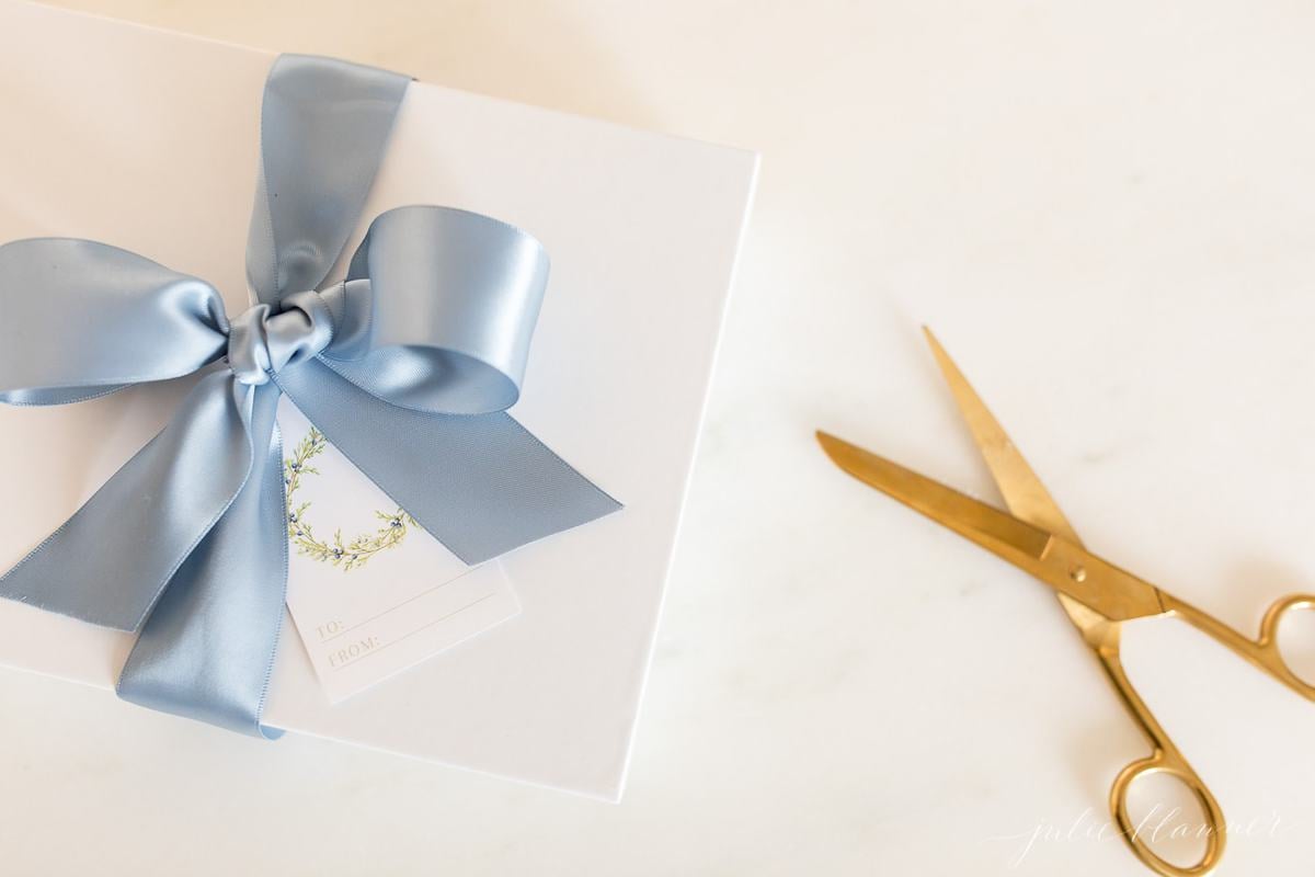 free printable christmas gift tags with a green wreath on a white package tied with blue satin ribbon.