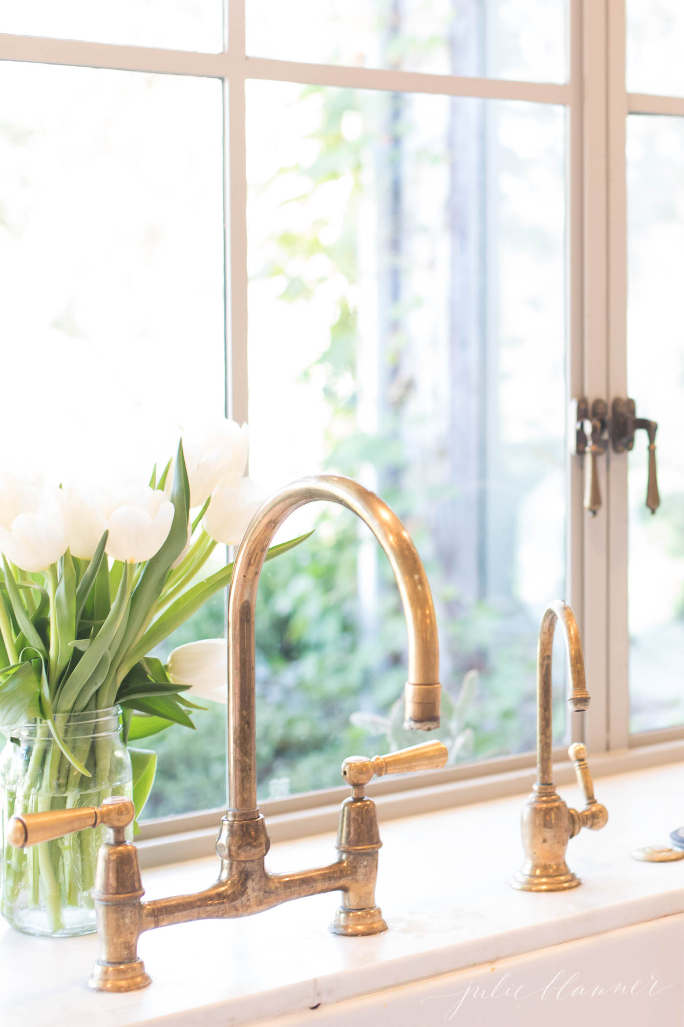 patina farm kitchen sink with an unlacquered brass faucet.