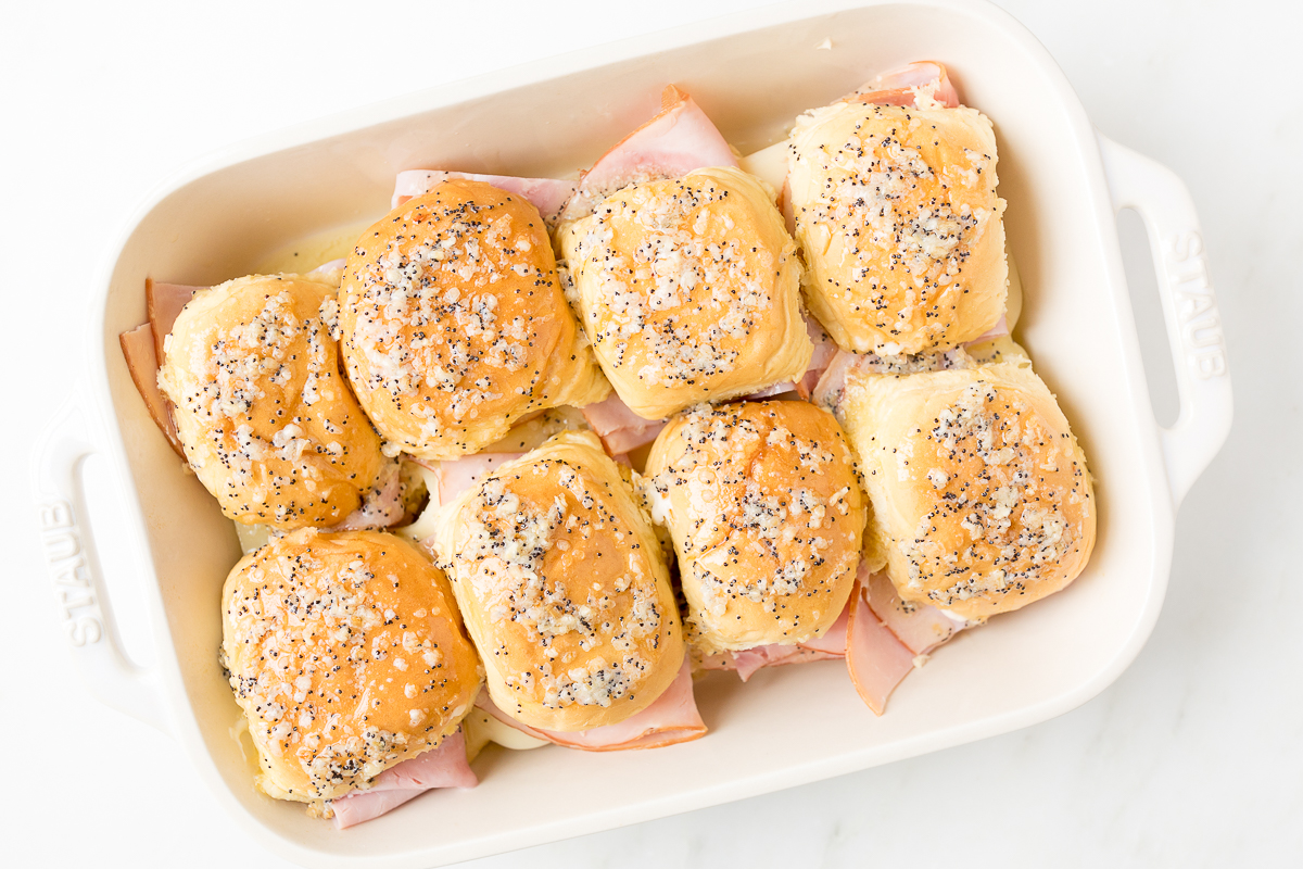 Hot ham and cheese sliders baked in a dish.