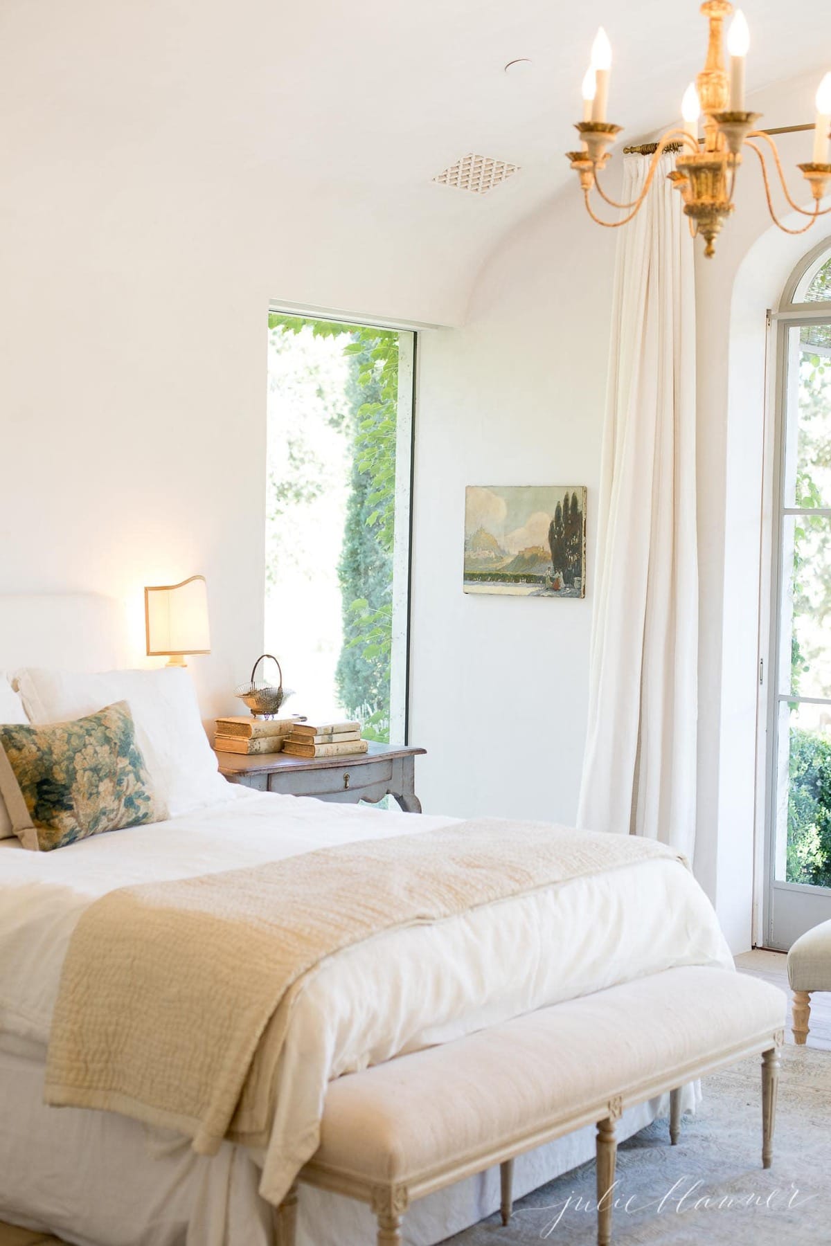 A vintage inspired bedroom with white walls, white bedding and white curtains