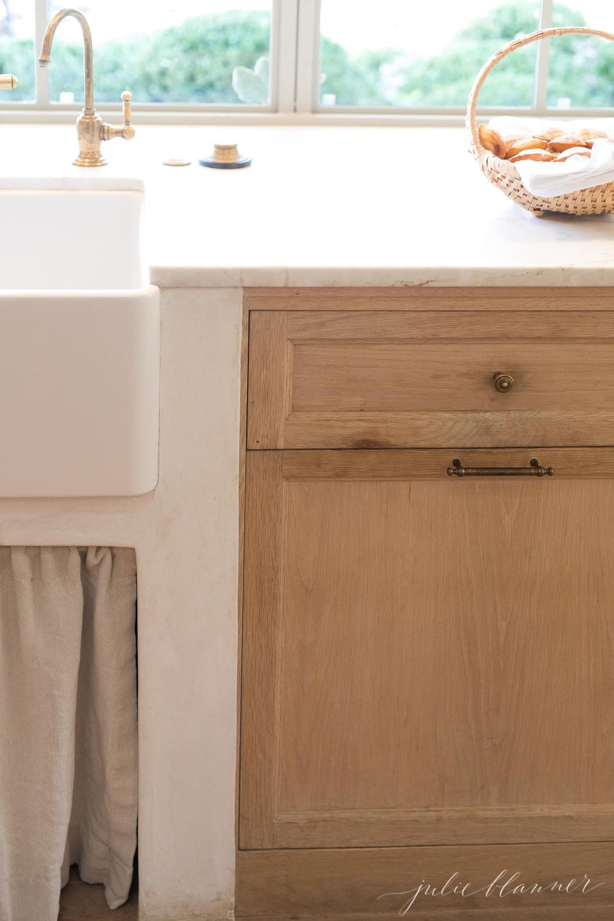 Patina Farm kitchen, with a farm sink, marble countertops and soft wood cabinets.