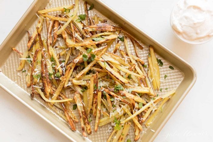 Truffle fries on a sheet. pan, topped with parmesan cheese and parsley.