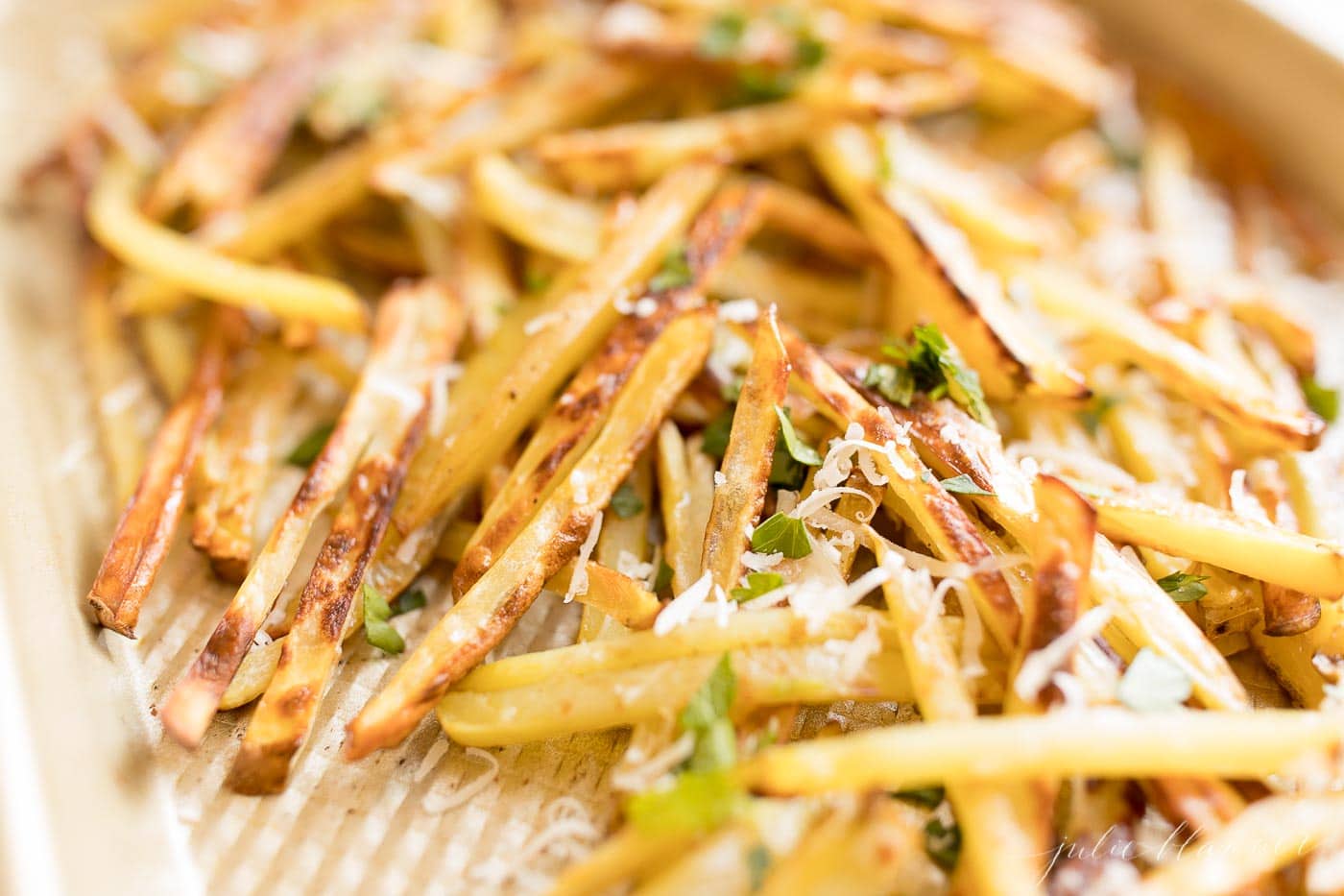 Truffle fries on a sheet pan, topped with parmesan cheese and parsley.