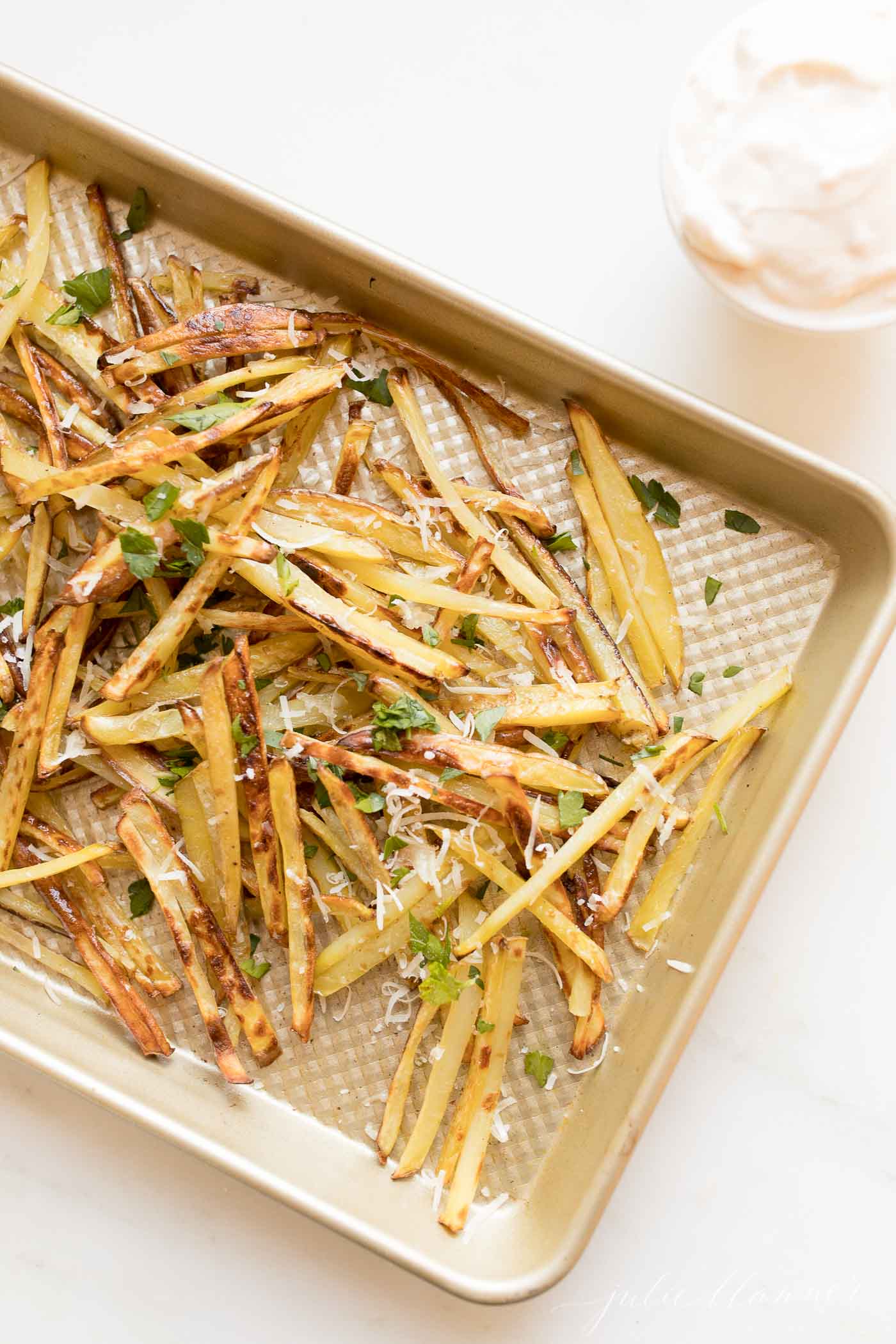 Truffle fries on a sheet. pan, topped with parmesan cheese and parsley.