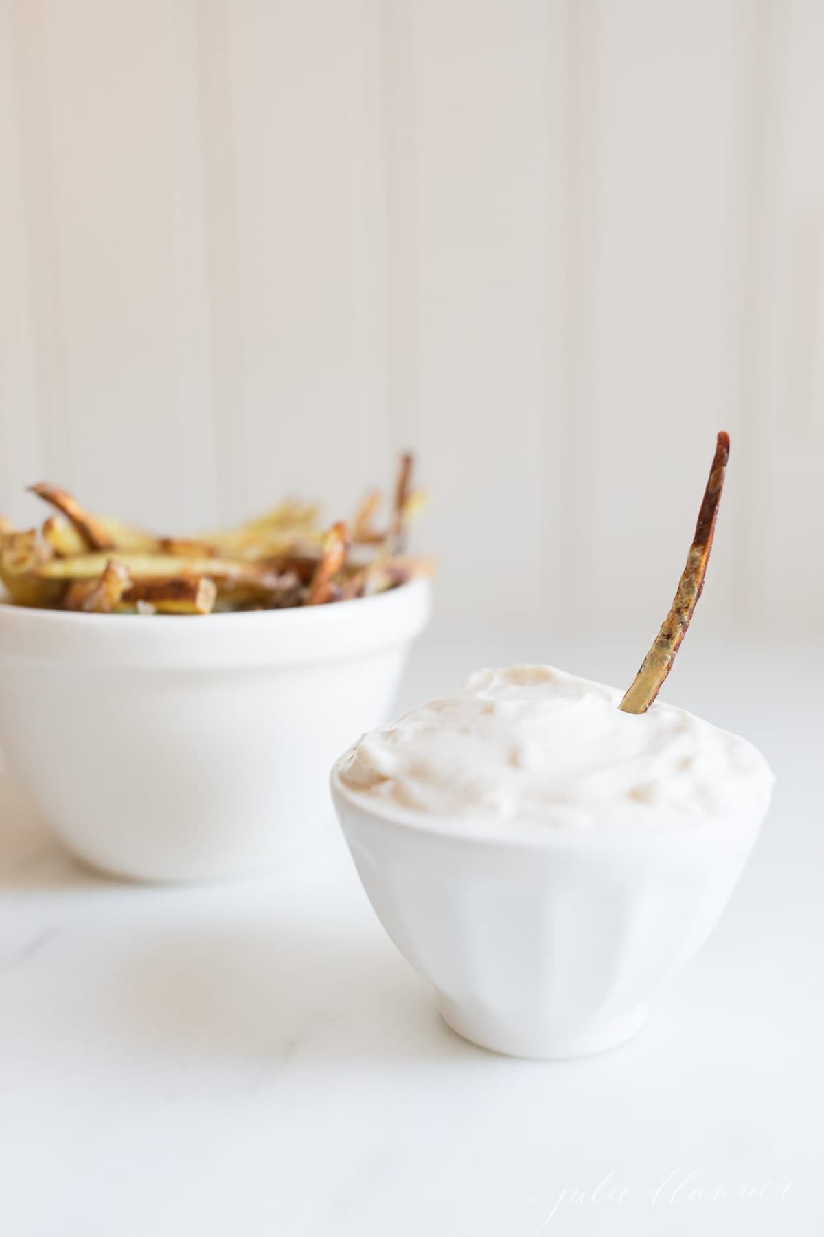 truffle mayo in a white bowl with fries in the background.