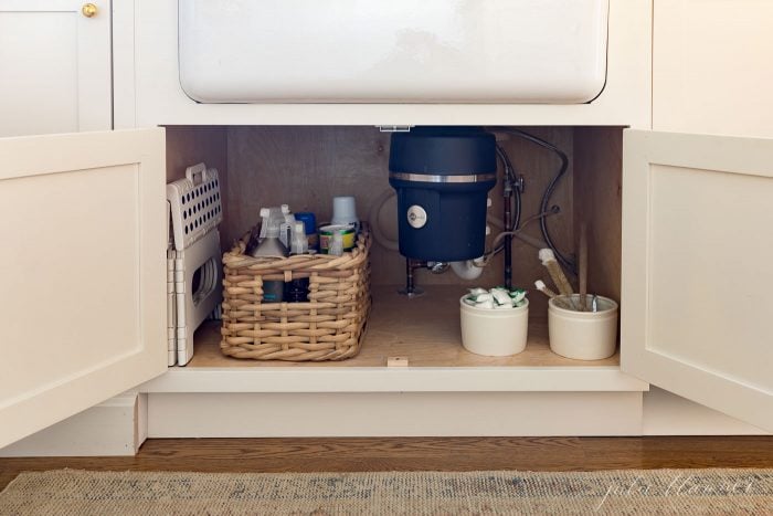 under sink cabinet organized with baskets and tubs.