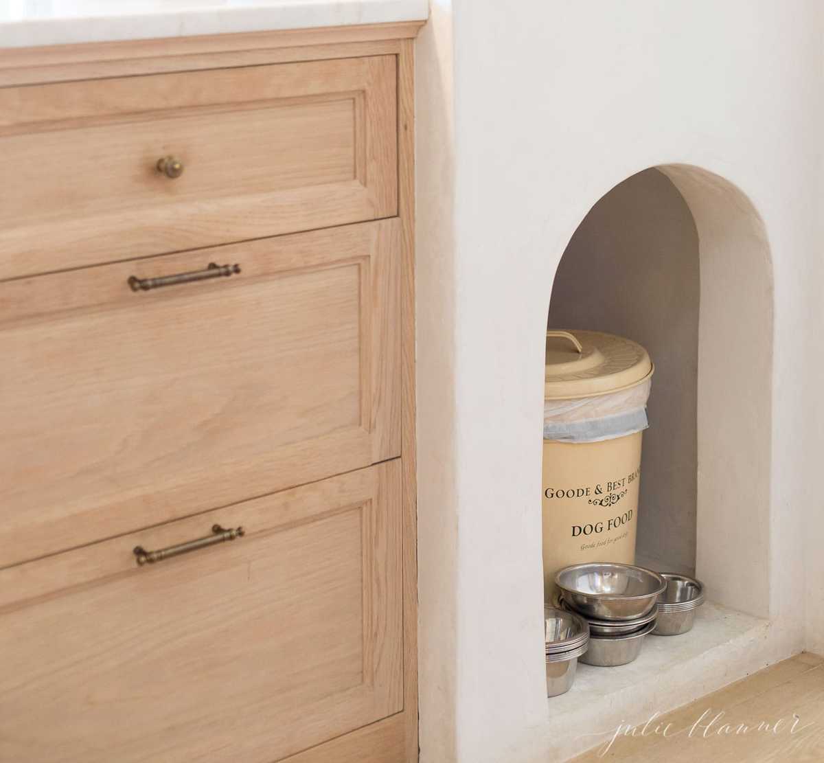 Soft wooden cabinets in the Patina Farm kitchen, with a small cutout for dog food and bowls.