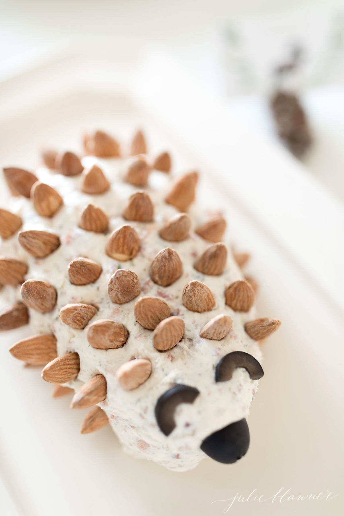 cheese spread with almonds on a platter for a Thanksgiving appetizer, shaped like a hedgehog