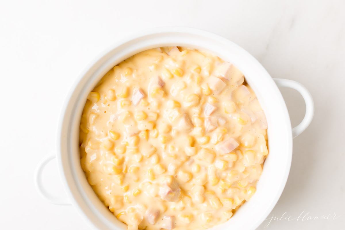 A white casserole dish filled with Cheesy Corn Casserole. 