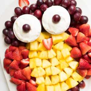A fruit tray shaped into an owl, featuring cream cheese fruit dip as the owl's eyes.