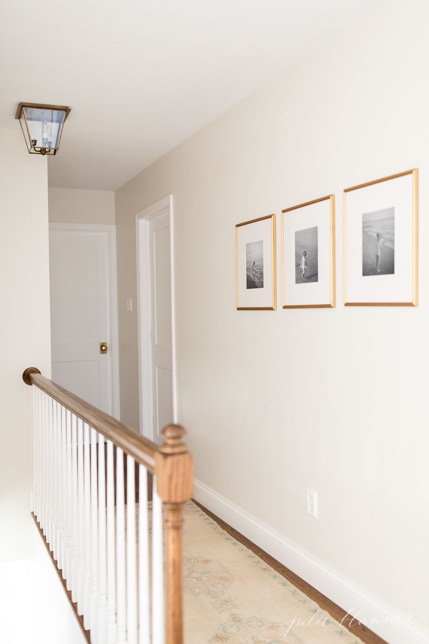 small hallway with white walls and brass framed photos