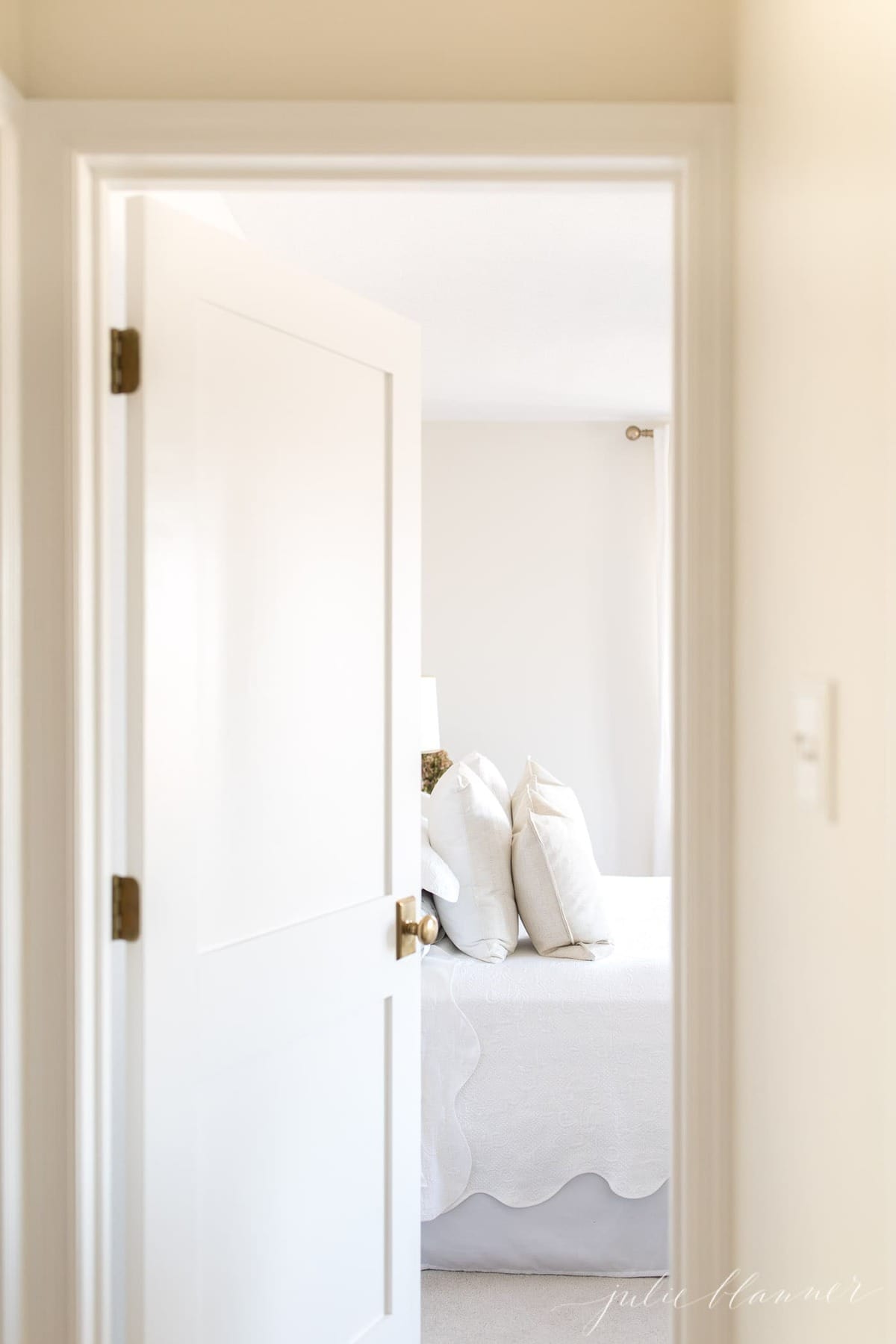A white door opening into a white bedroom