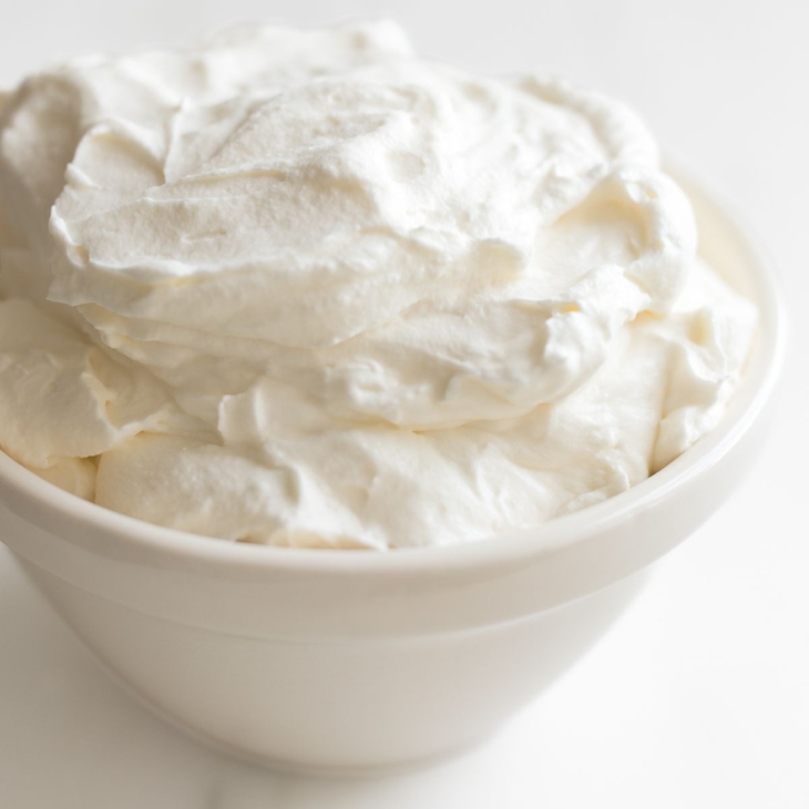 A white bowl full of homemade whipped cream.