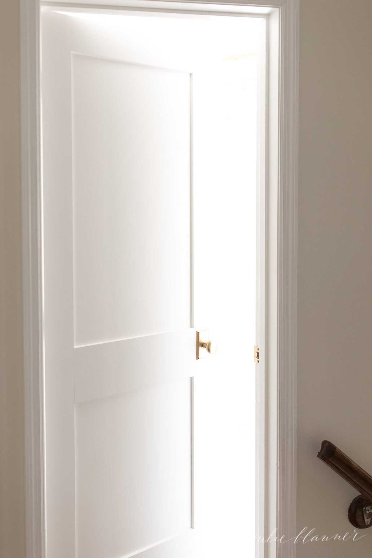 A small hallway with a white door opening into a bedroom