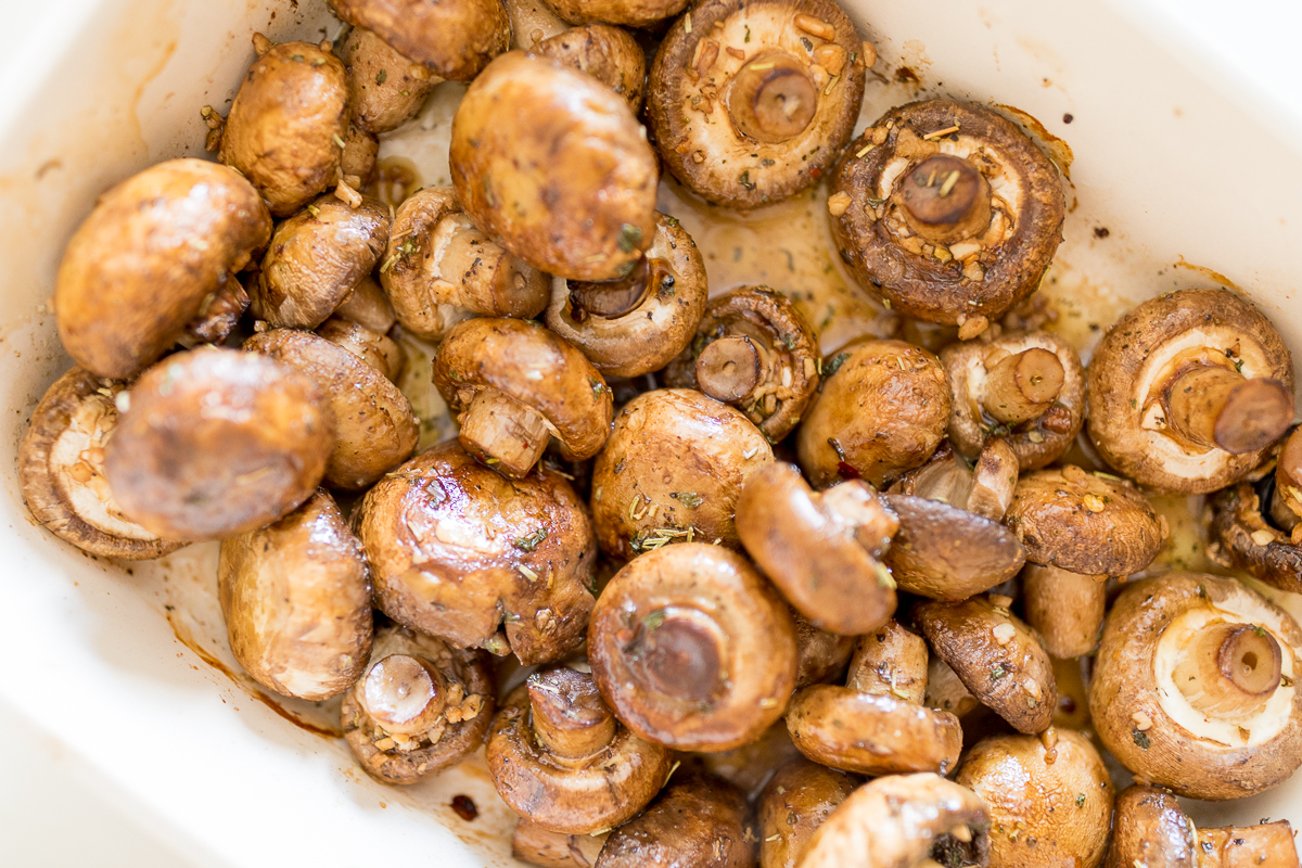 Garlic-infused, oven-roasted mushrooms presented in a white baking dish.