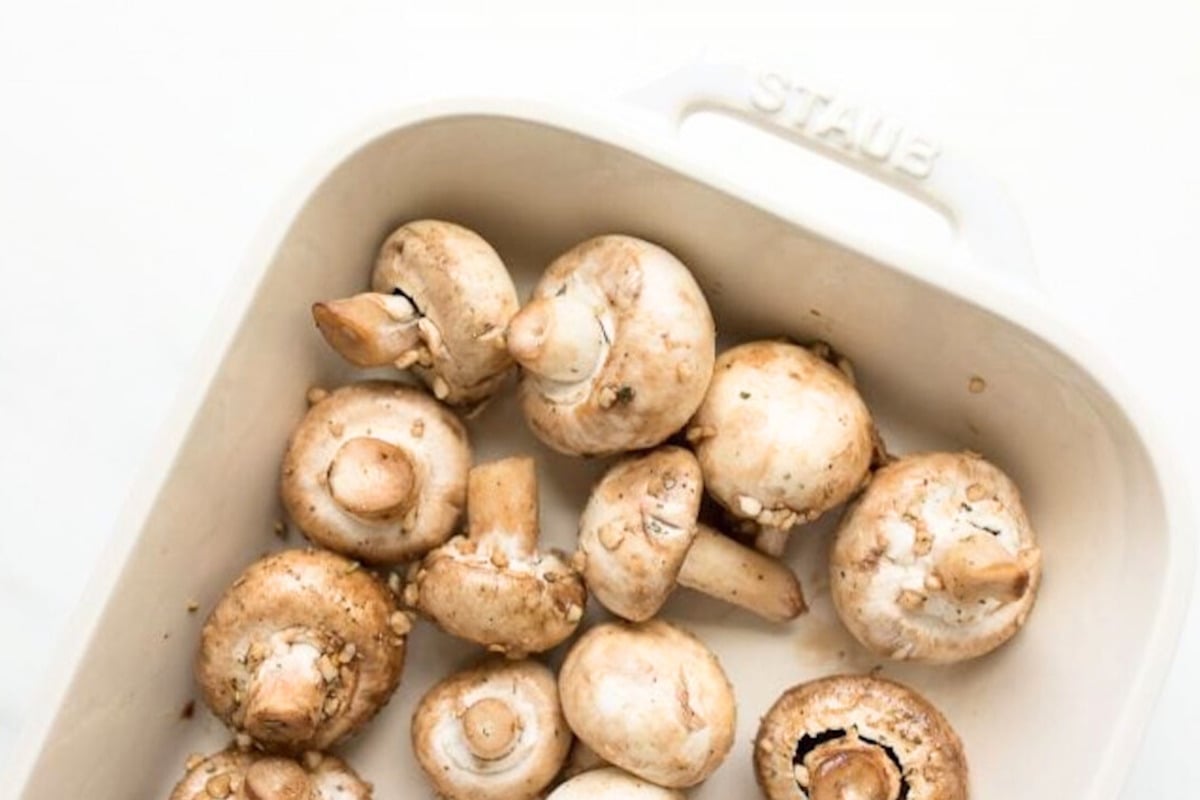 Roasted mushrooms in a white baking dish, drizzled with garlic for added flavor.