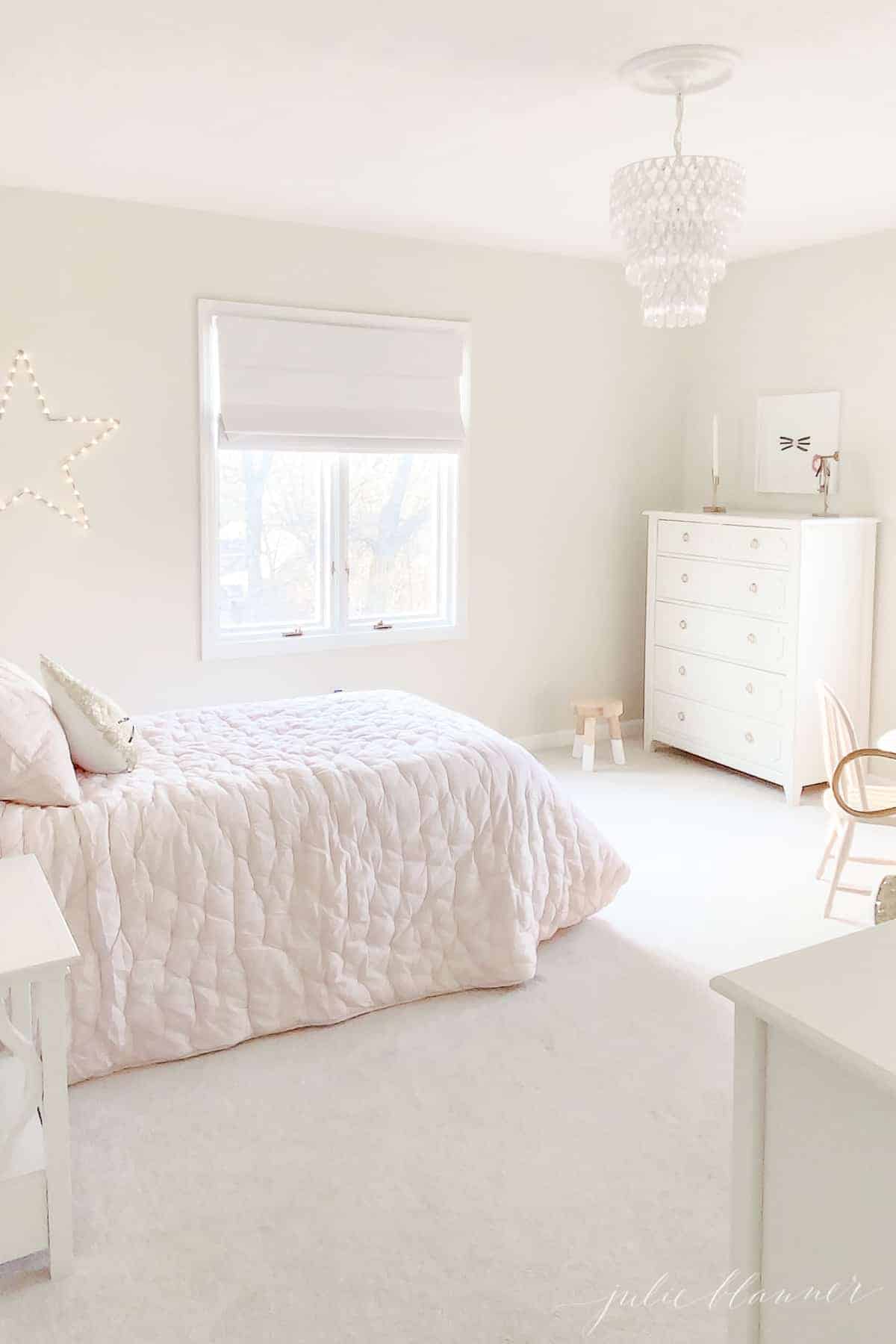 pink and cream bedroom with white dresser and crystal light