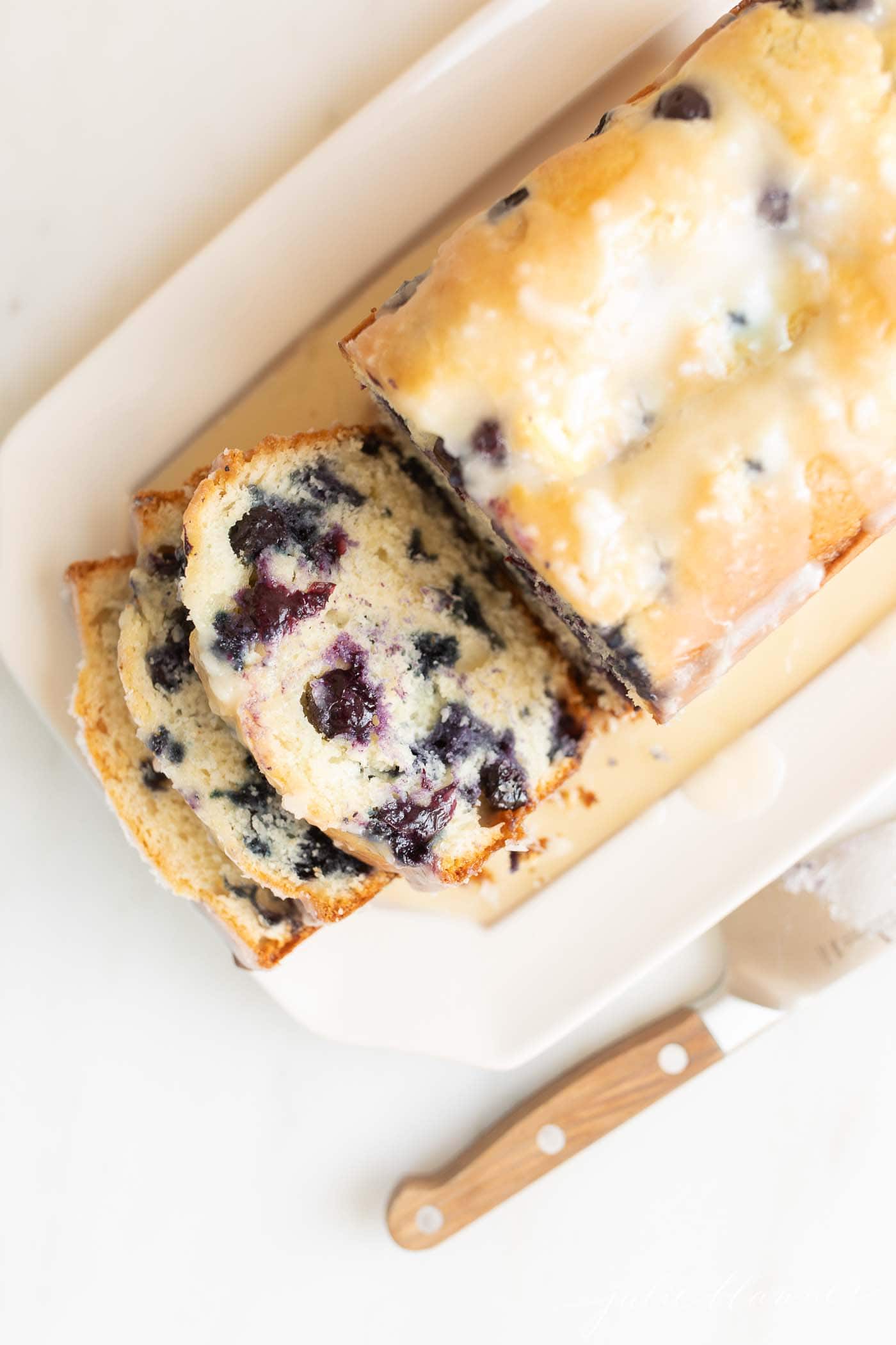 sliced blueberry bread on a platter with knife next to it
