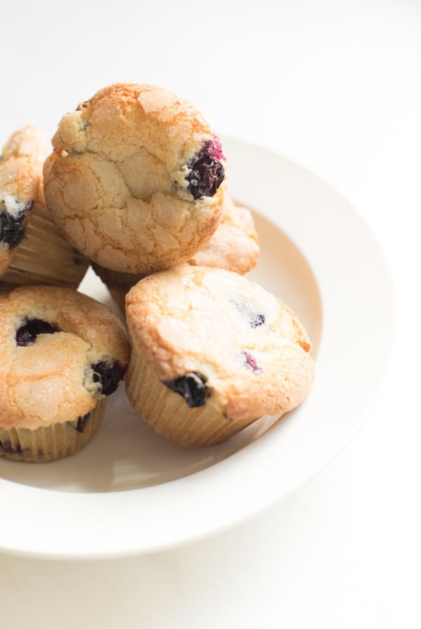 A plate of freshly baked, easy blueberry muffins on a white background.