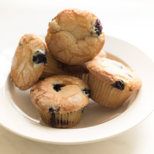 A plate containing five easy blueberry muffins on a white background.