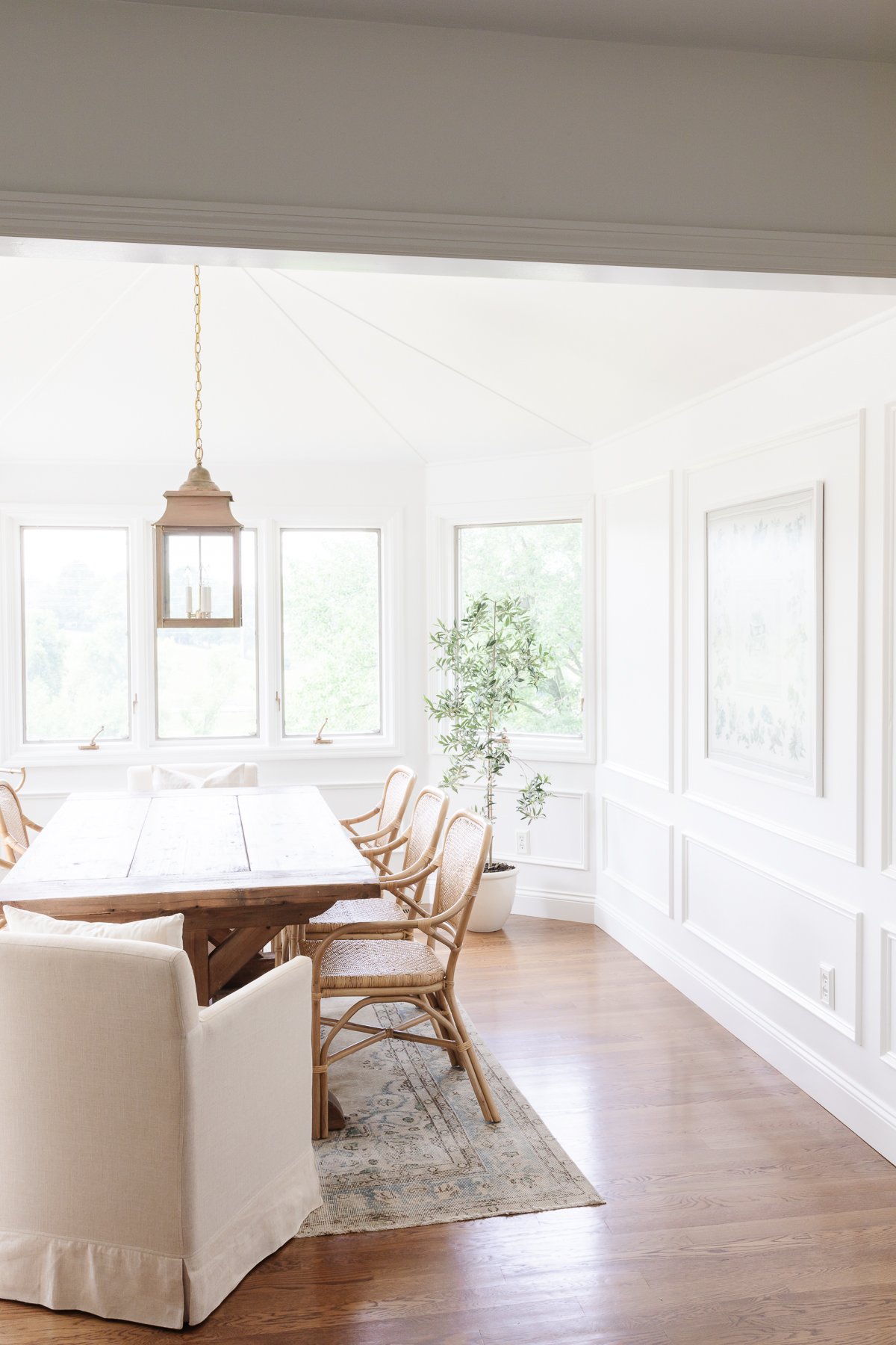 A white windowed breakfast nook with a wood dining table.