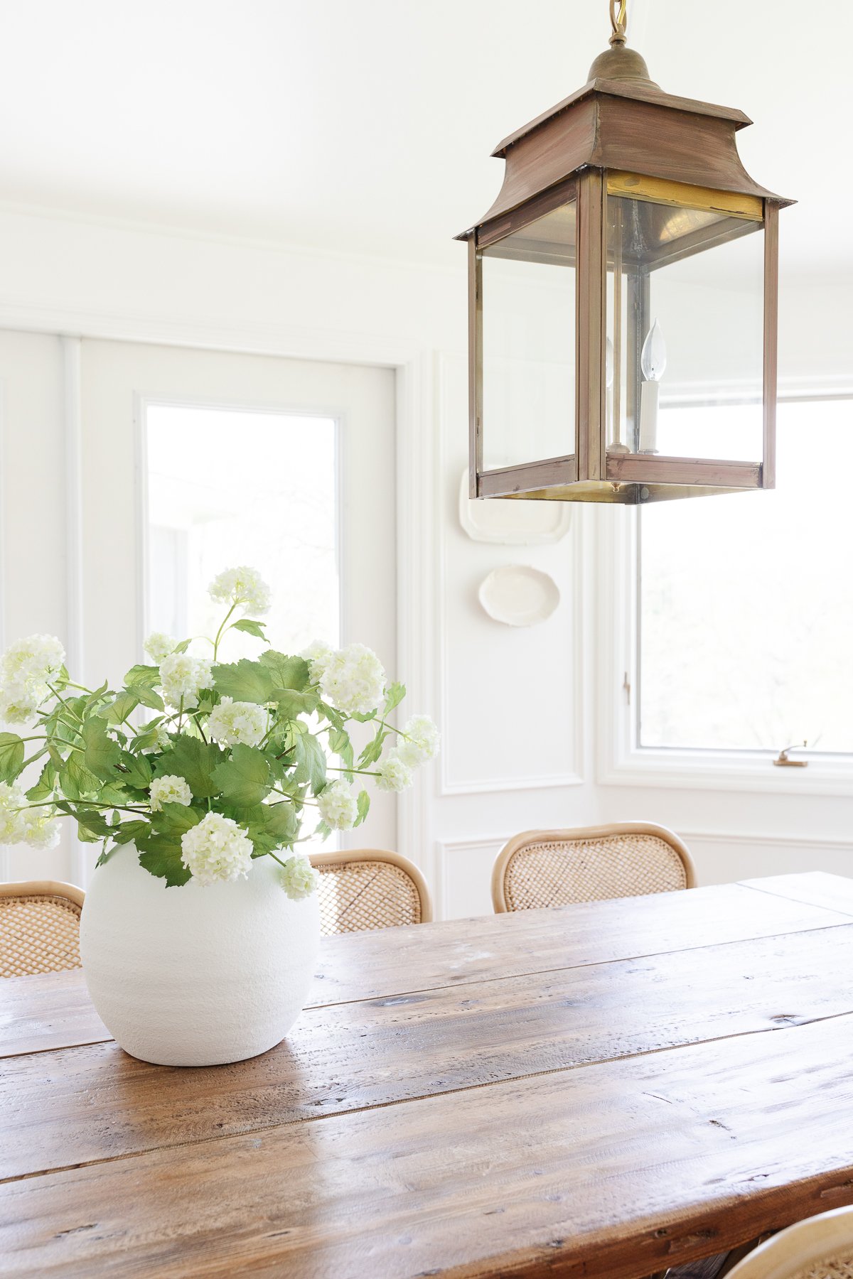 A white windowed breakfast nook with a wood dining table.