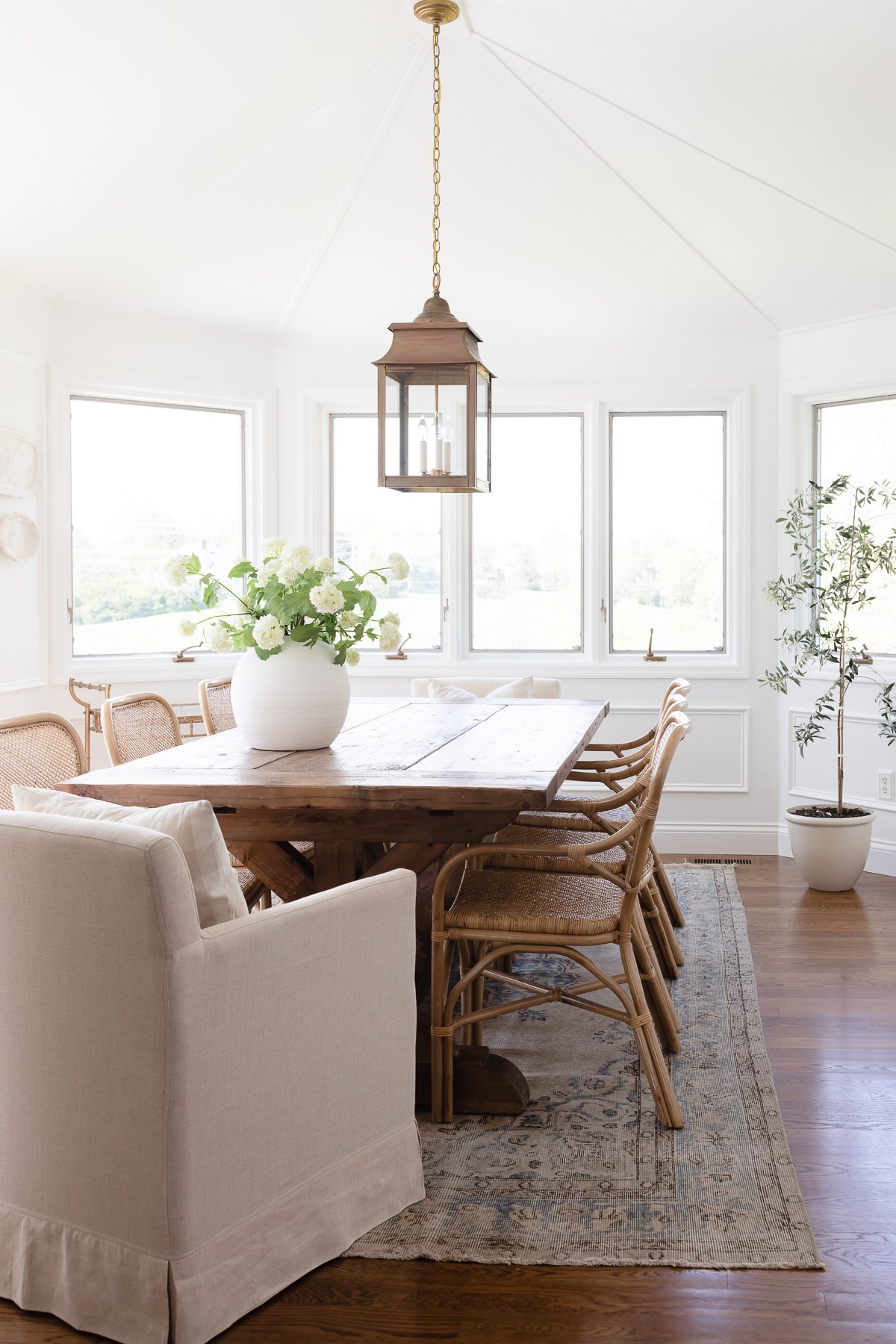 A white windowed breakfast nook with a wood dining table.