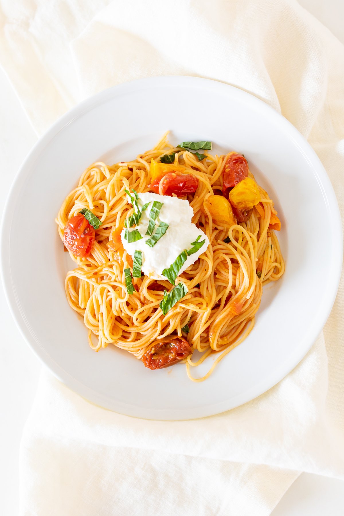 A white plate full of cherry tomato pasta.