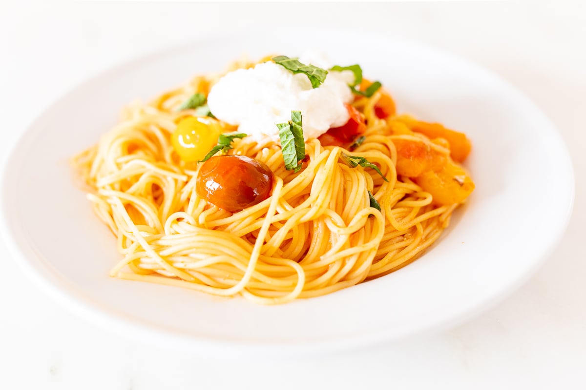 A white plate full of cherry tomato pasta.